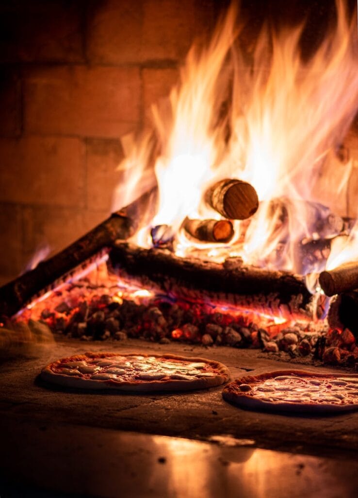 Delicious pizzas cooking in a traditional wood-fired oven, radiating warmth and flavor.