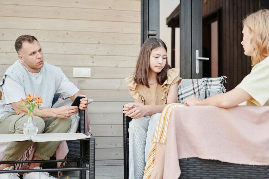 A family of three having a serious conversation outdoors on a patio.