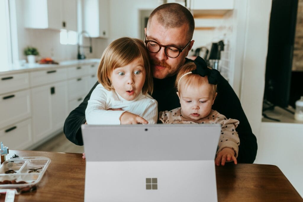 a man and two children looking at a laptop