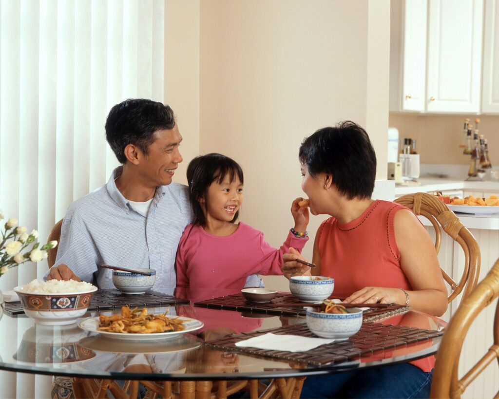 a man, woman and child sitting at a table eating food, Family Food Adventure