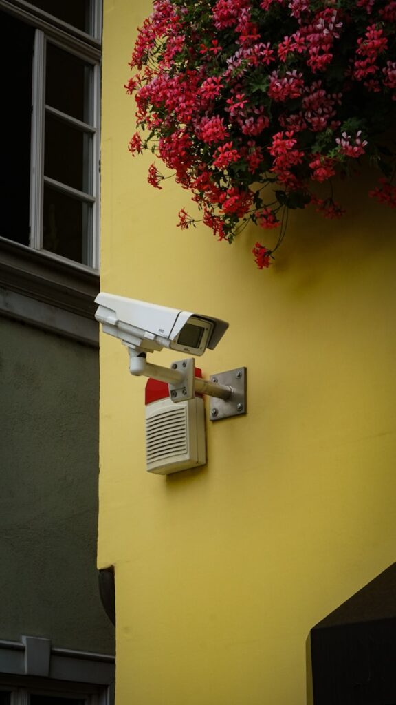 white and gray security camera mounted on yellow painted wall, home security systems