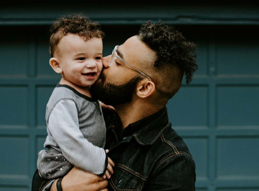 man carrying baby boy and kissing on cheek. Fatherhood Tips That Transform: 7 Powerful Dad Strategies 💪